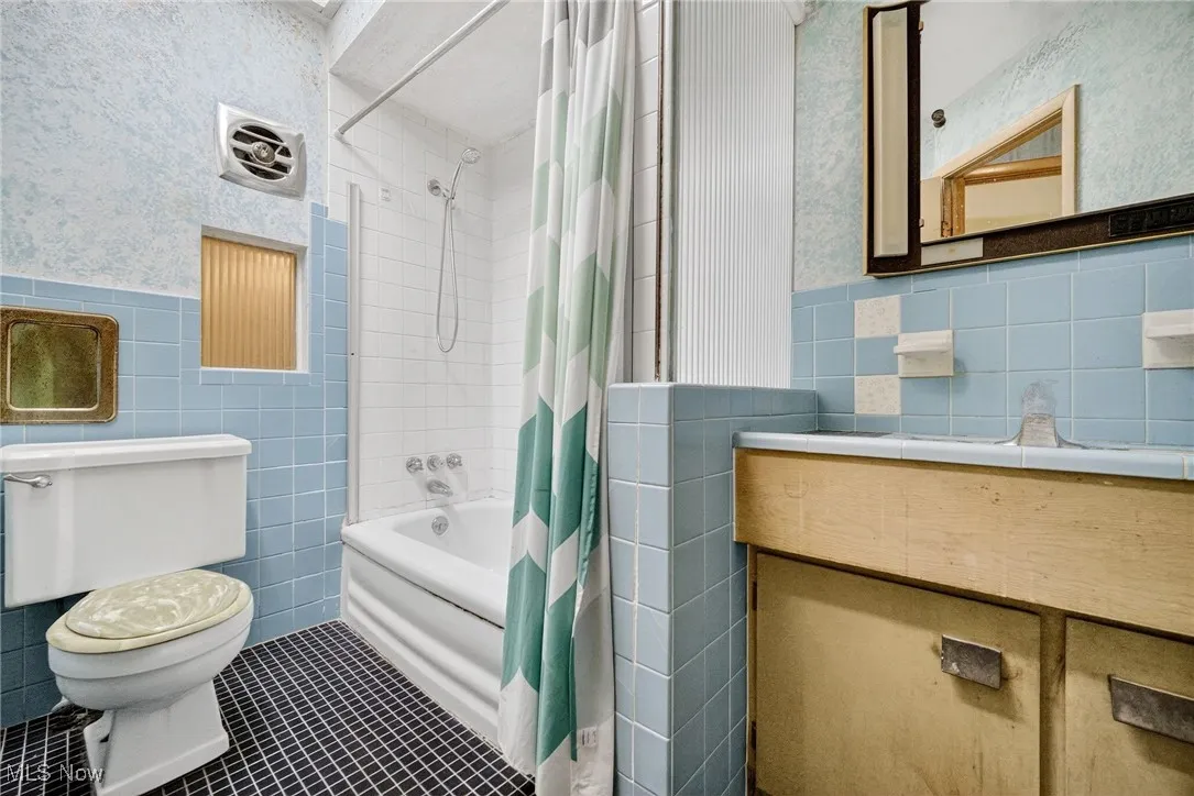 Full bathroom featuring, tile walls, tile patterned flooring, shower / bath combination with curtain, and vanity