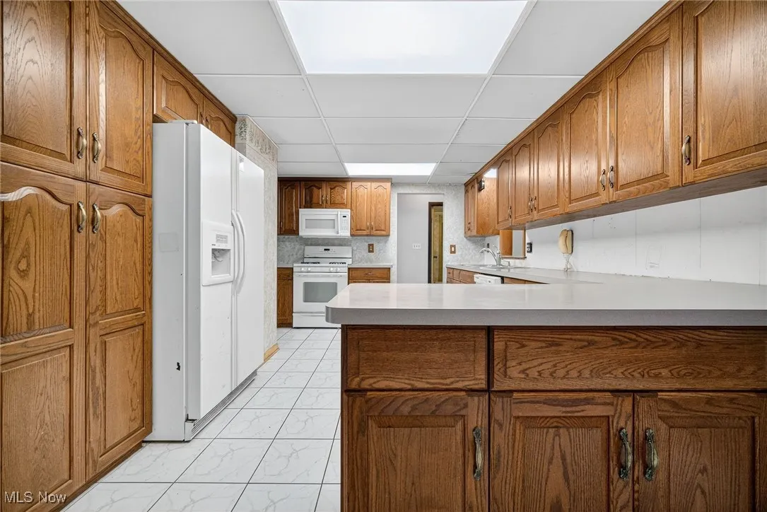 Kitchen with plenty of cabinet space, white appliances, light ceramic floors.