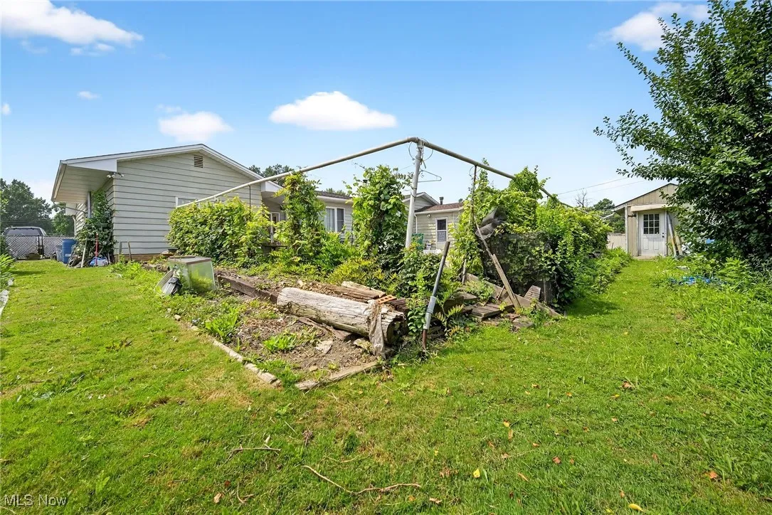 Rear view of property with a yard and a vegetable garden