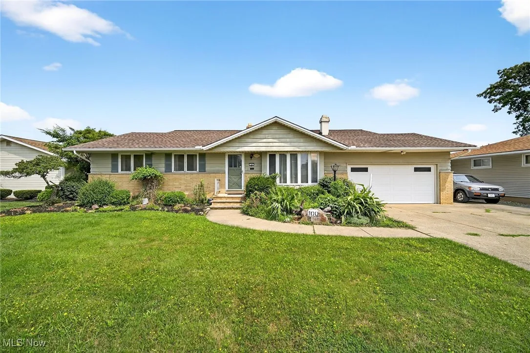 Ranch-style house with concrete driveway with additional parking pad, a front yard, brick siding, and an attached 2 car garage