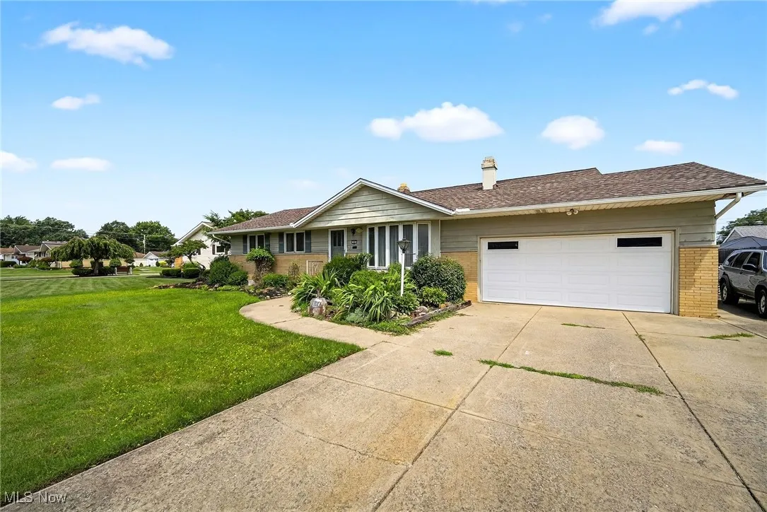 Ranch-style house featuring brick siding, a garage, a front yard, concrete driveway, and a chimney