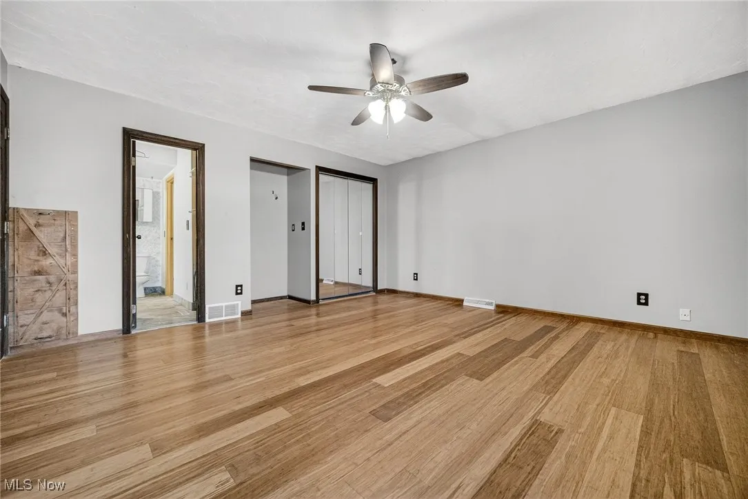 Primary Bedroom bamboo wood finished floors, Jack & Jill  bathroom, and a ceiling fan
