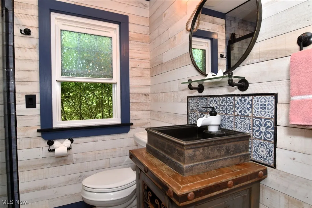 Full bathroom on main floor featuring wood walls, vanity and one window
