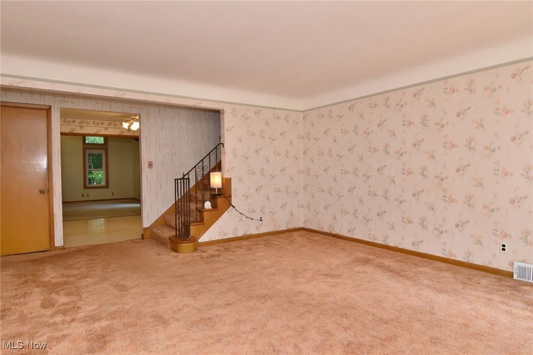 View from door. Carpeted living room with hardwood floors beneath