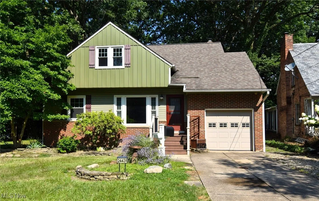 View of front facade with driveway, board and batten siding, brick siding, a front lawn, and a garage