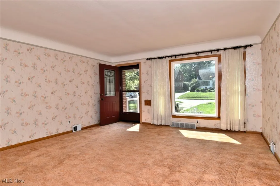 View from dining area. Carpeted living room with hardwood floors beneath