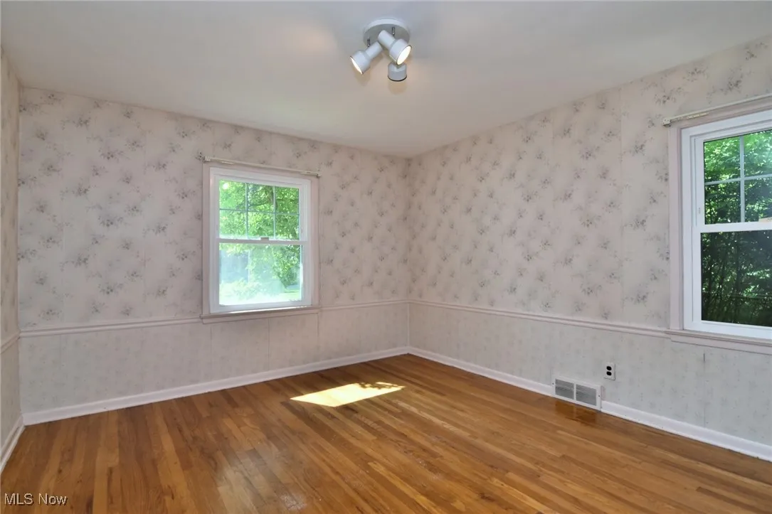 Bedroom #1, main floor featuring hardwood flooring and two windows
