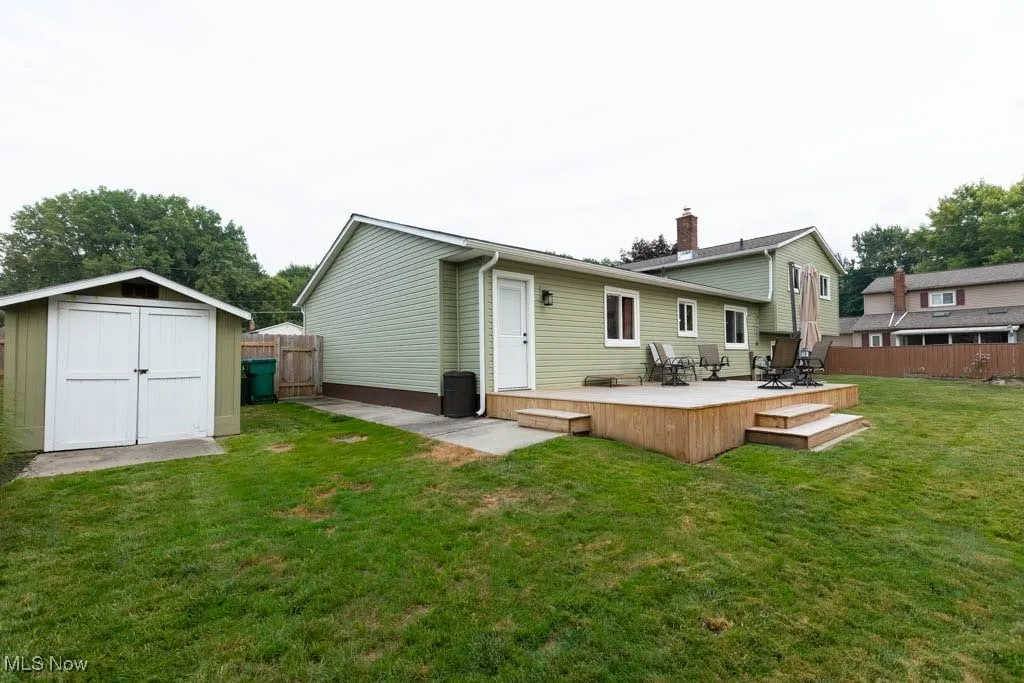 Back of house with a shed, a fenced backyard, a deck, and outdoor dining area