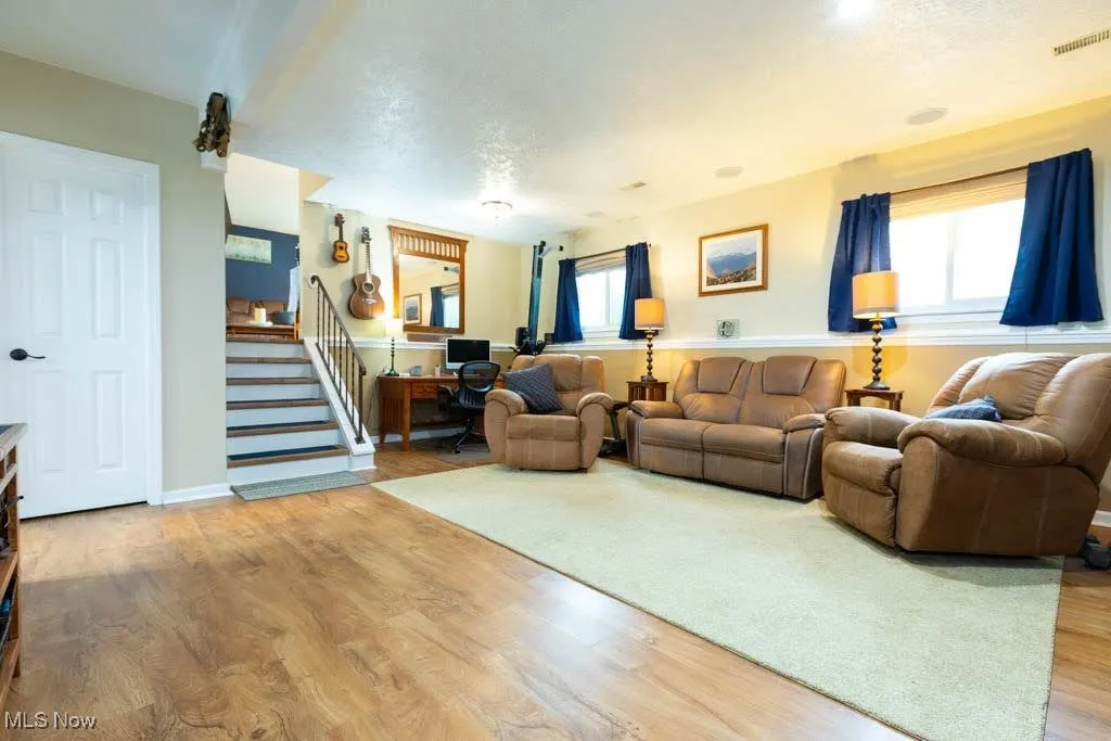 Living area featuring a desk, wood finished floors, stairs, and a textured ceiling