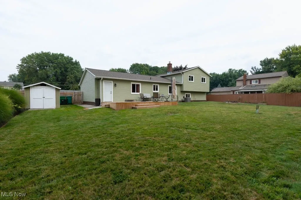 Back of house featuring a storage shed and a wooden deck