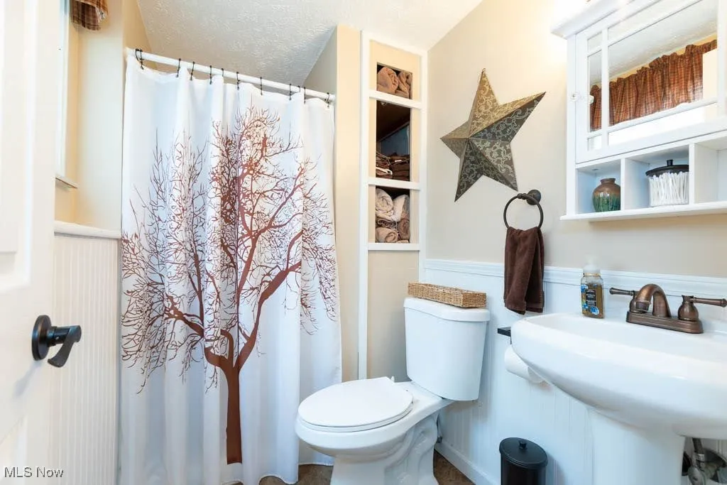 Full bath with wainscoting and a shower with curtain