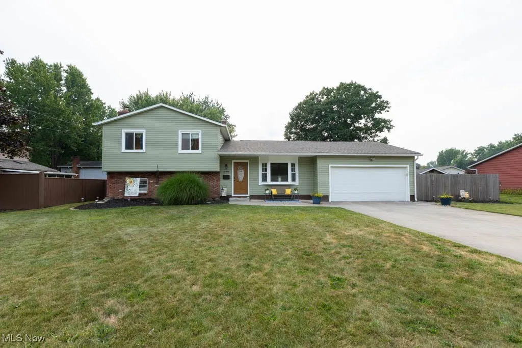 Tri-level home with an attached garage, driveway, and brick siding