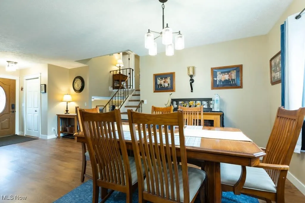 Dining area with stairs, wood finished floors, and a chandelier