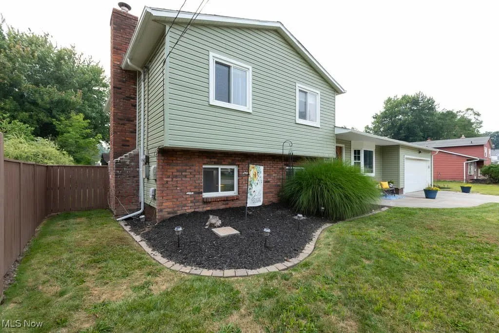 Back of property with a chimney, brick siding, and an attached garage