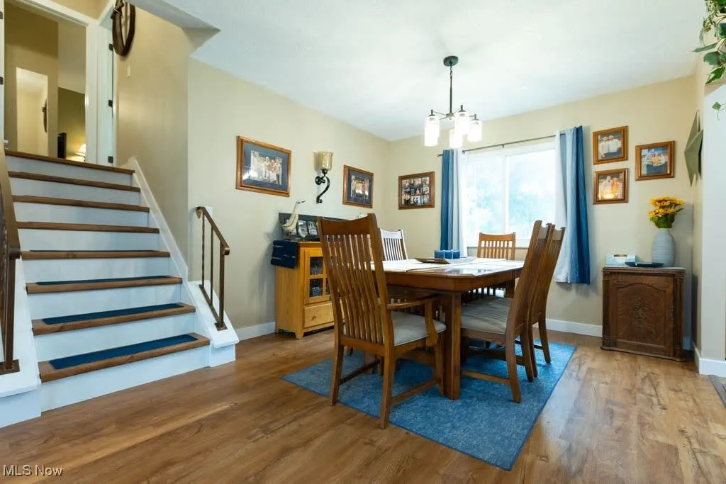 Dining room featuring wood finished floors, a chandelier, and stairs