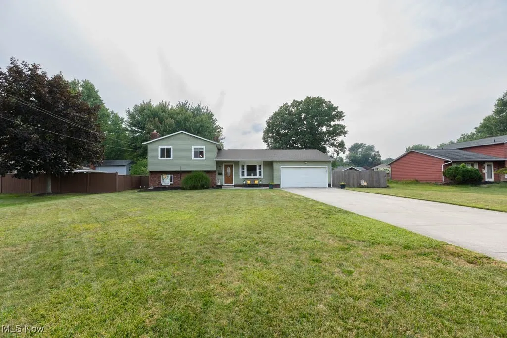 Split level home featuring driveway, an attached garage, and brick siding