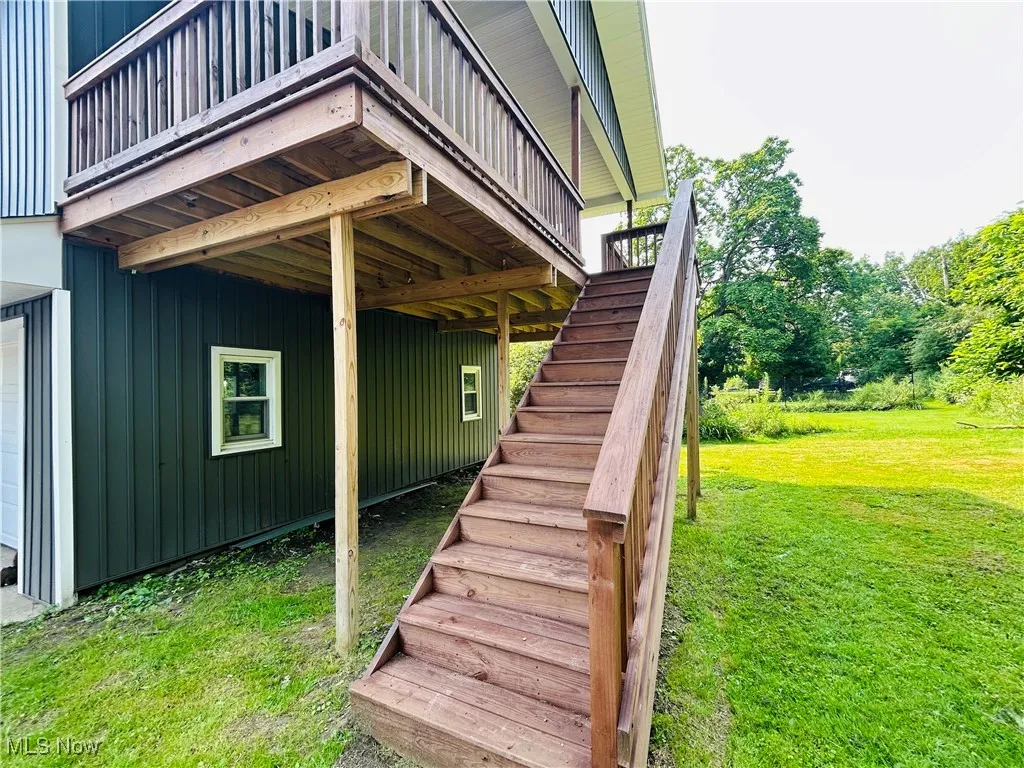View of exterior entry featuring a yard, a garage, and board and batten siding. Private entrance, additional living suite.