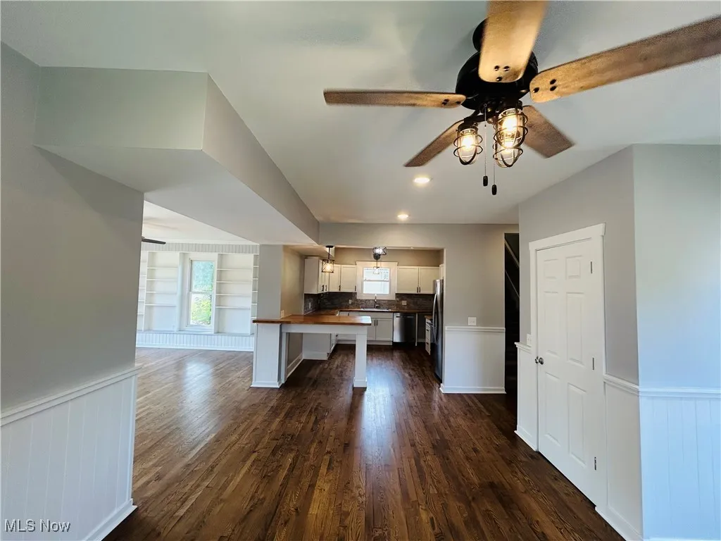 Kitchen featuring wainscoting, dark wood-style floors, open floor plan, white cabinets, and stainless steel appliances