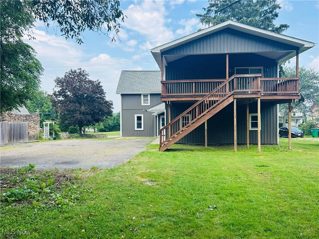 Back of property with stairway, a yard, and a deck
