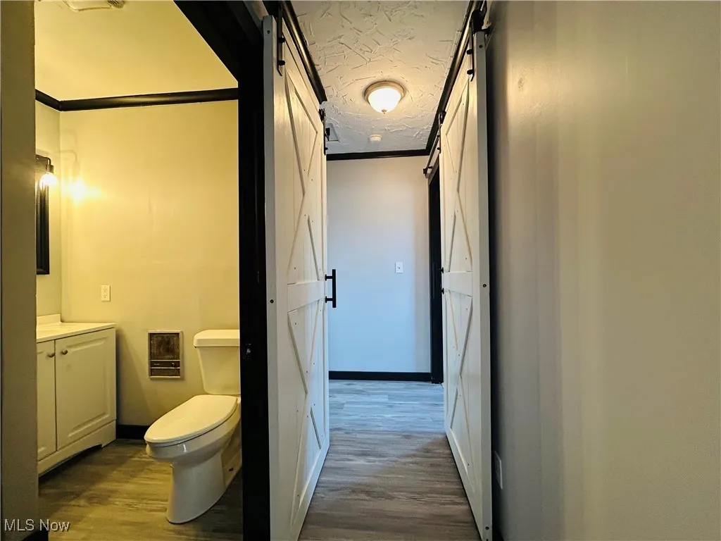 Bathroom with a textured ceiling, crown molding, vanity, and wood finished floors, additional living suite.