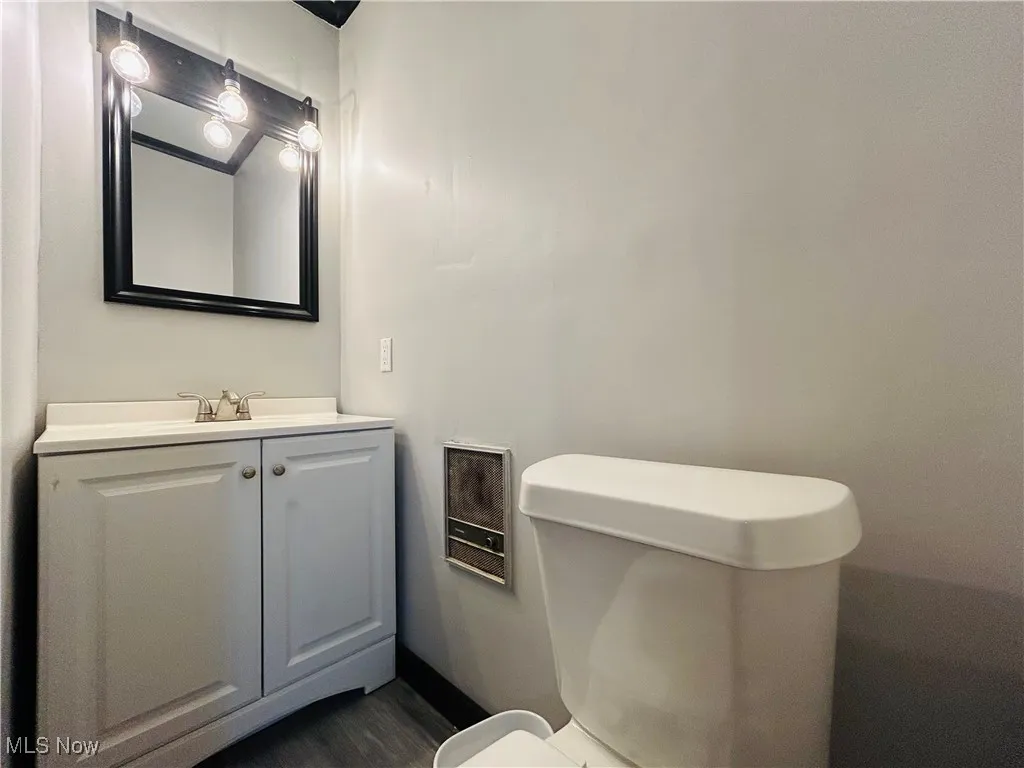 Half bath featuring vanity and wood finished floors, additional living suite.