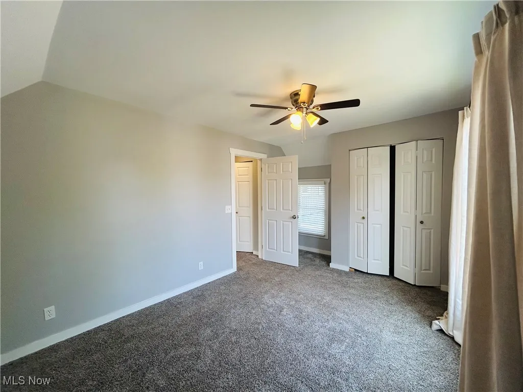 Unfurnished bedroom with carpet, a ceiling fan, a closet, and vaulted ceiling