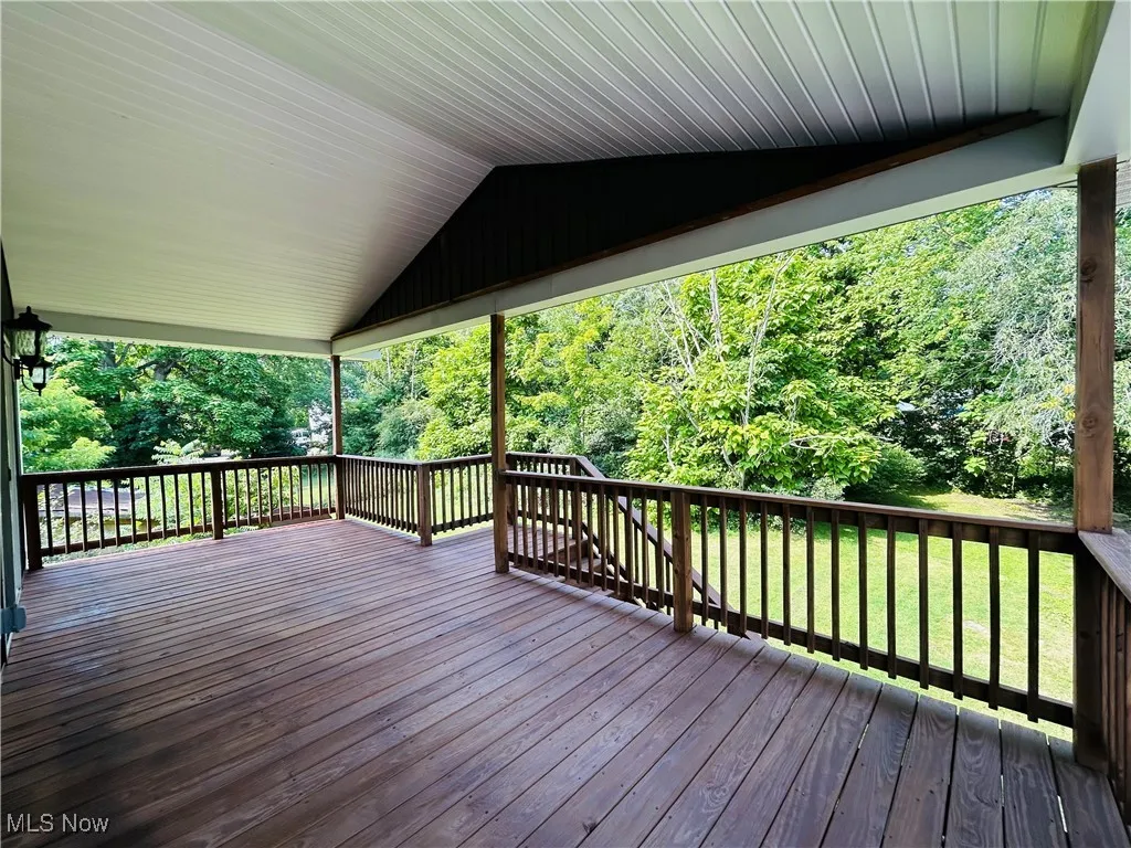 Wooden terrace with a lawn and a view of trees, additional living suite.