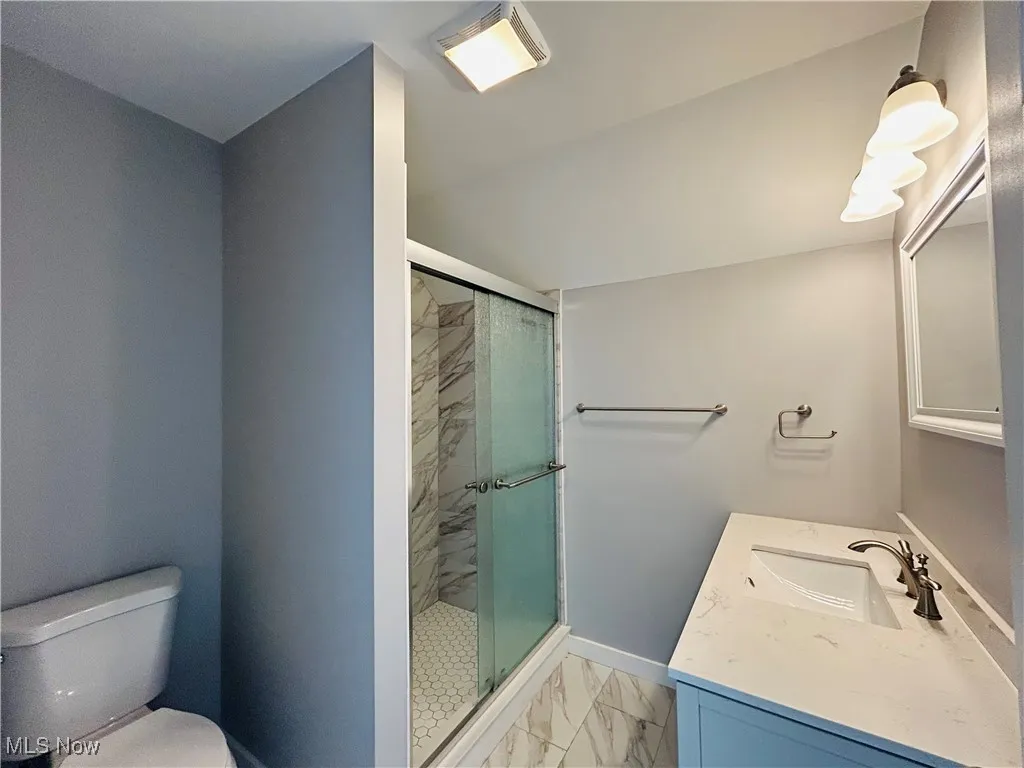 Full bath featuring marble finish flooring, vanity, and a stall shower