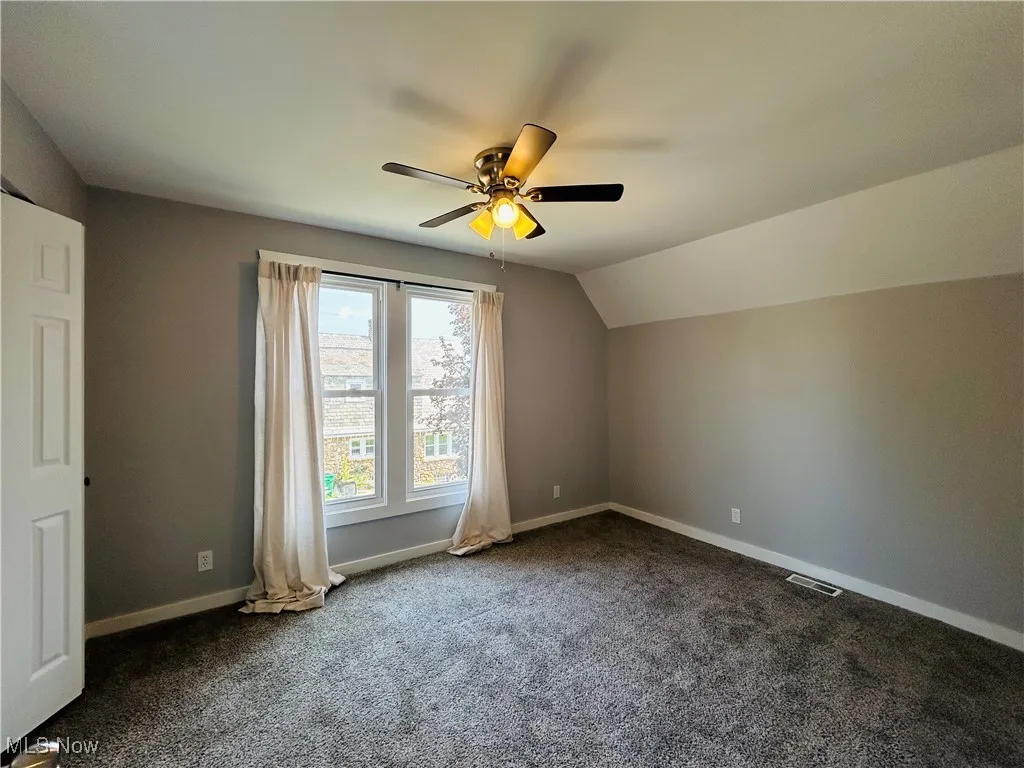 Bonus room with dark carpet, lofted ceiling, and a ceiling fan