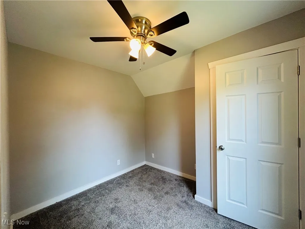Unfurnished bedroom featuring carpet flooring, lofted ceiling, and a ceiling fan