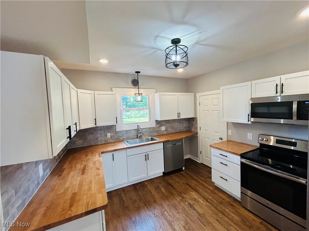 Kitchen with butcher block counters, stainless steel appliances, recessed lighting, decorative backsplash, and dark wood-style flooring