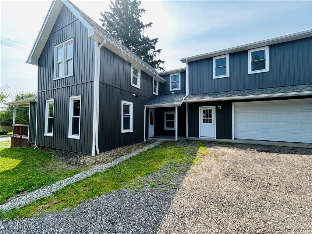 View of front of house featuring driveway, a garage, and a shingled roof