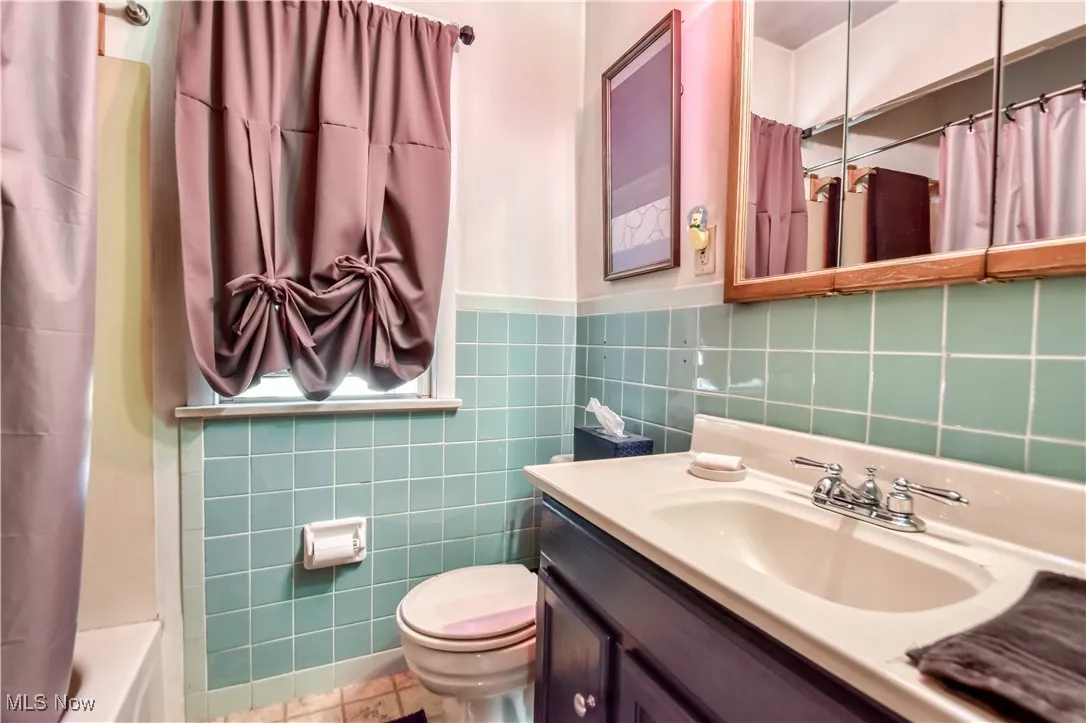 Bathroom with tile walls, vanity, wainscoting, and tile patterned floors