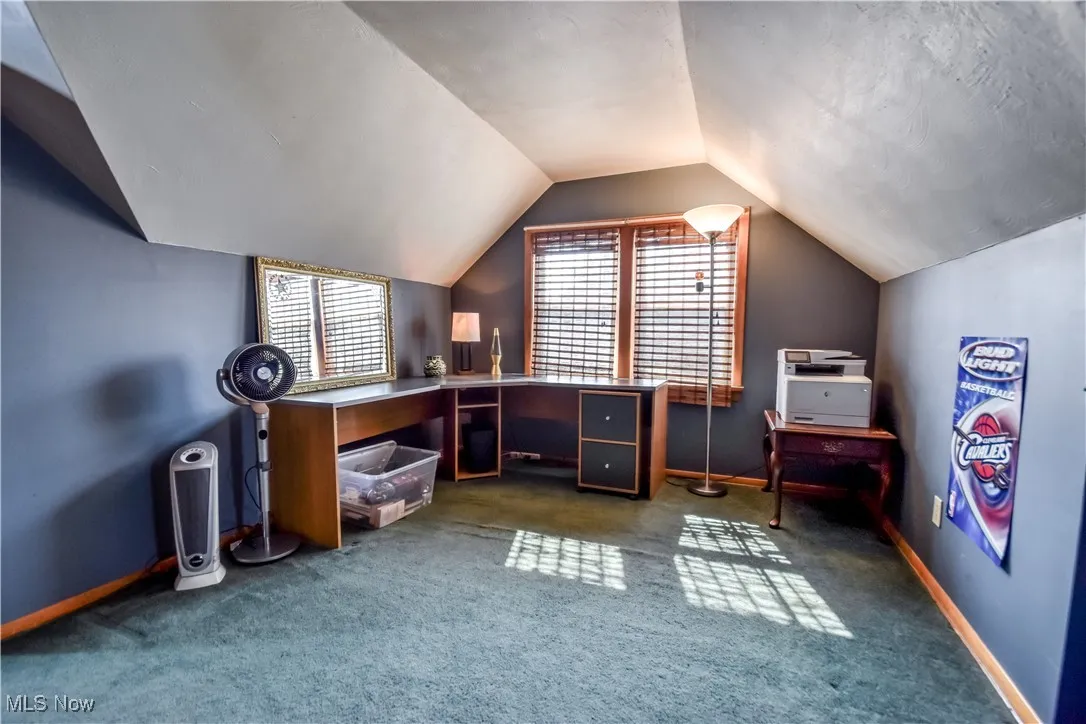 Home office featuring dark carpet and lofted ceiling