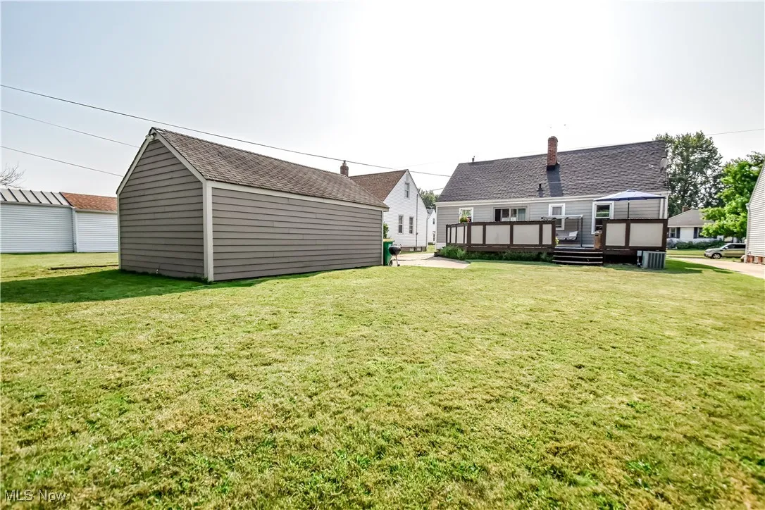 View of green lawn with a deck and an outdoor structure