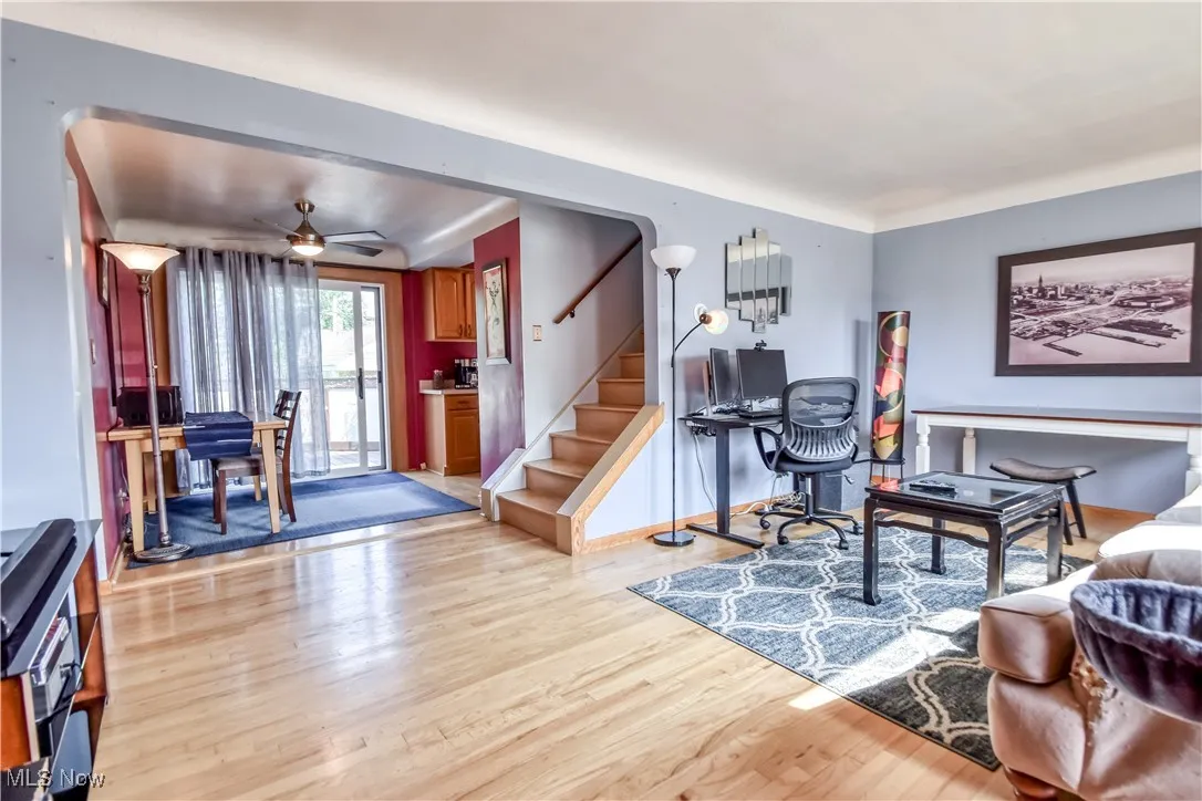 Living room with light wood-style floors, stairs, and ceiling fan