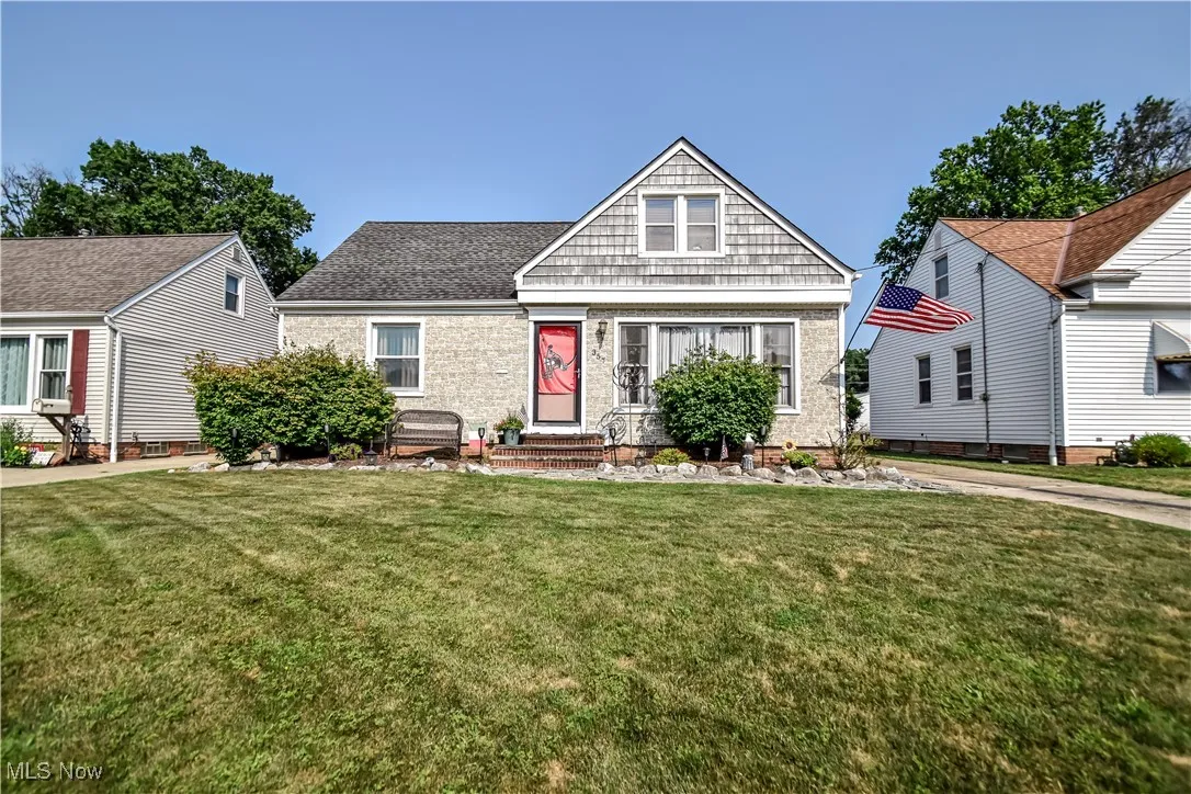 View of front of property with entry steps, a front lawn, and a shingled roof