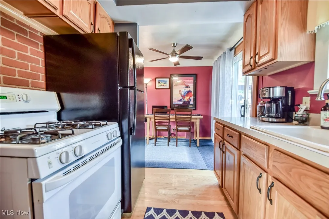Kitchen with gas range gas stove, light countertops, light wood-type flooring, and ceiling fan