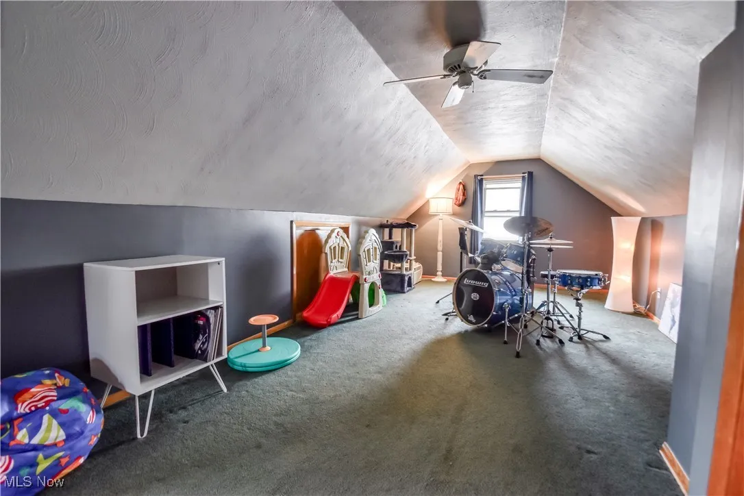 Playroom with a textured ceiling, carpet flooring, lofted ceiling, and a ceiling fan