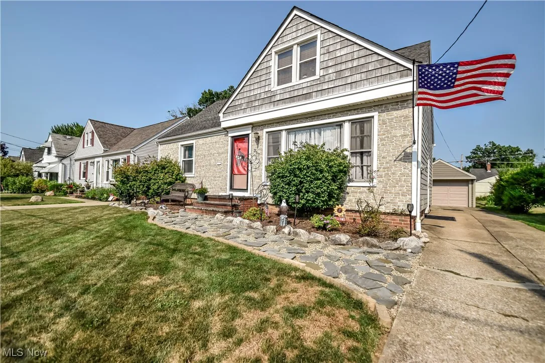 View of front facade featuring a front yard, an outdoor structure, a garage, and brick siding