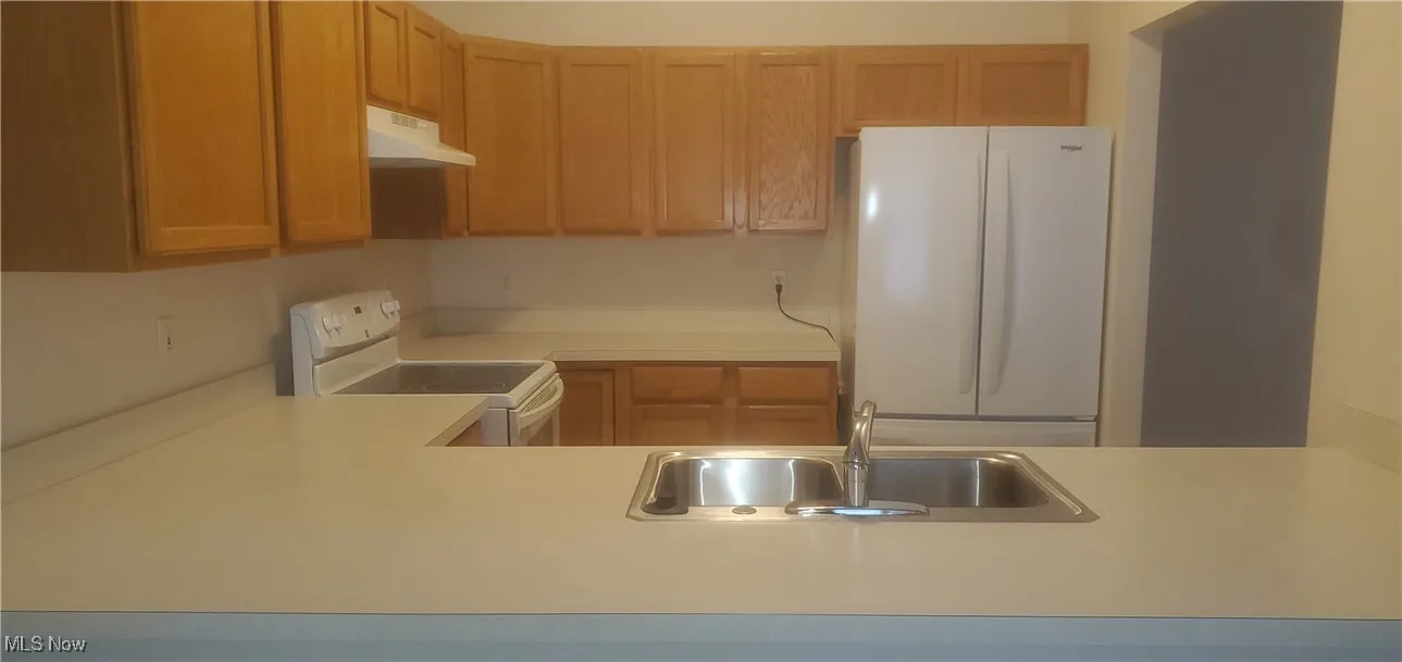 Kitchen featuring white appliances, light countertops, and custom exhaust hood