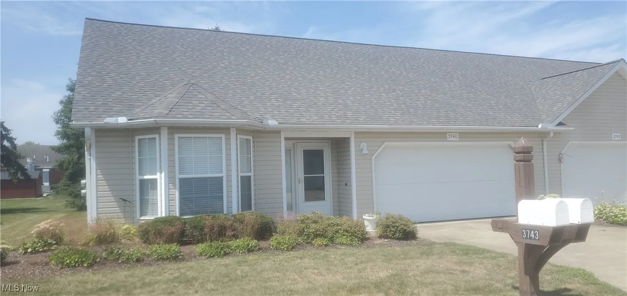 View of front of property with roof with shingles, a garage, driveway, and a front lawn