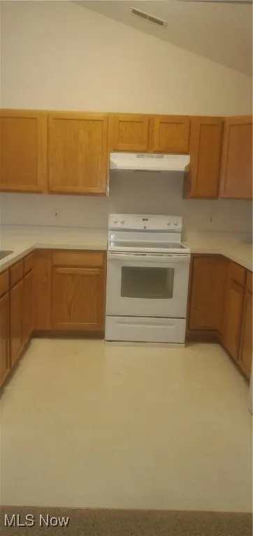 Kitchen featuring white electric range, lofted ceiling, light floors, exhaust hood, and light countertops