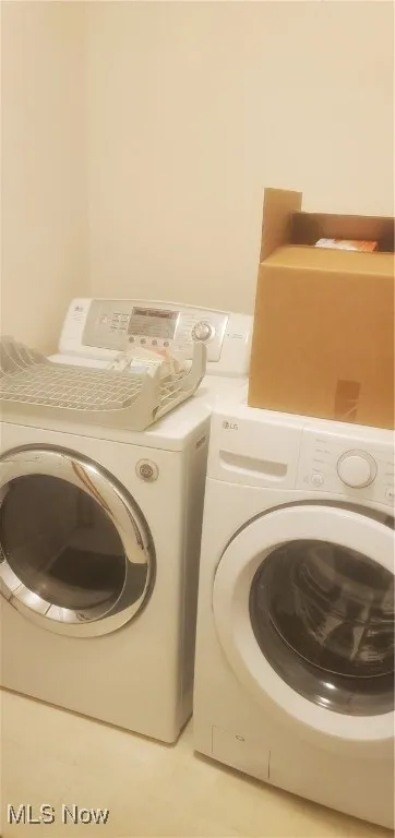 Laundry area with separate washer and dryer and light floors