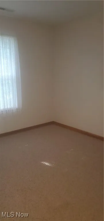 Carpeted empty room featuring baseboards