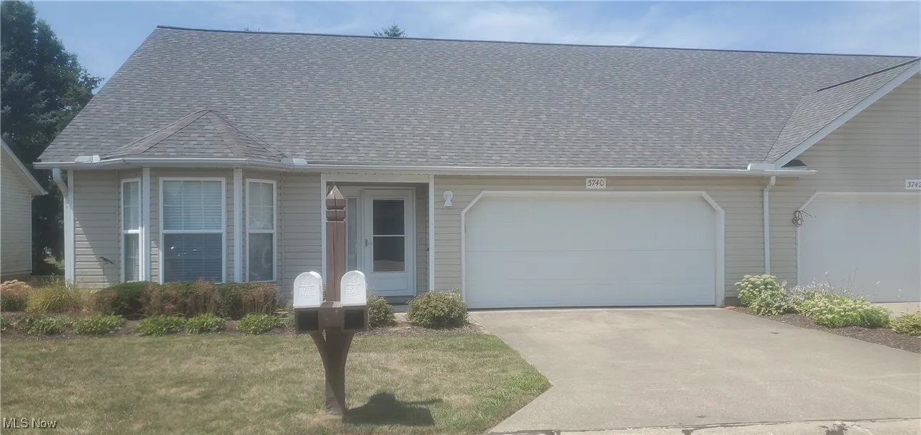 View of front of property with roof with shingles, concrete driveway, a garage, and a front yard