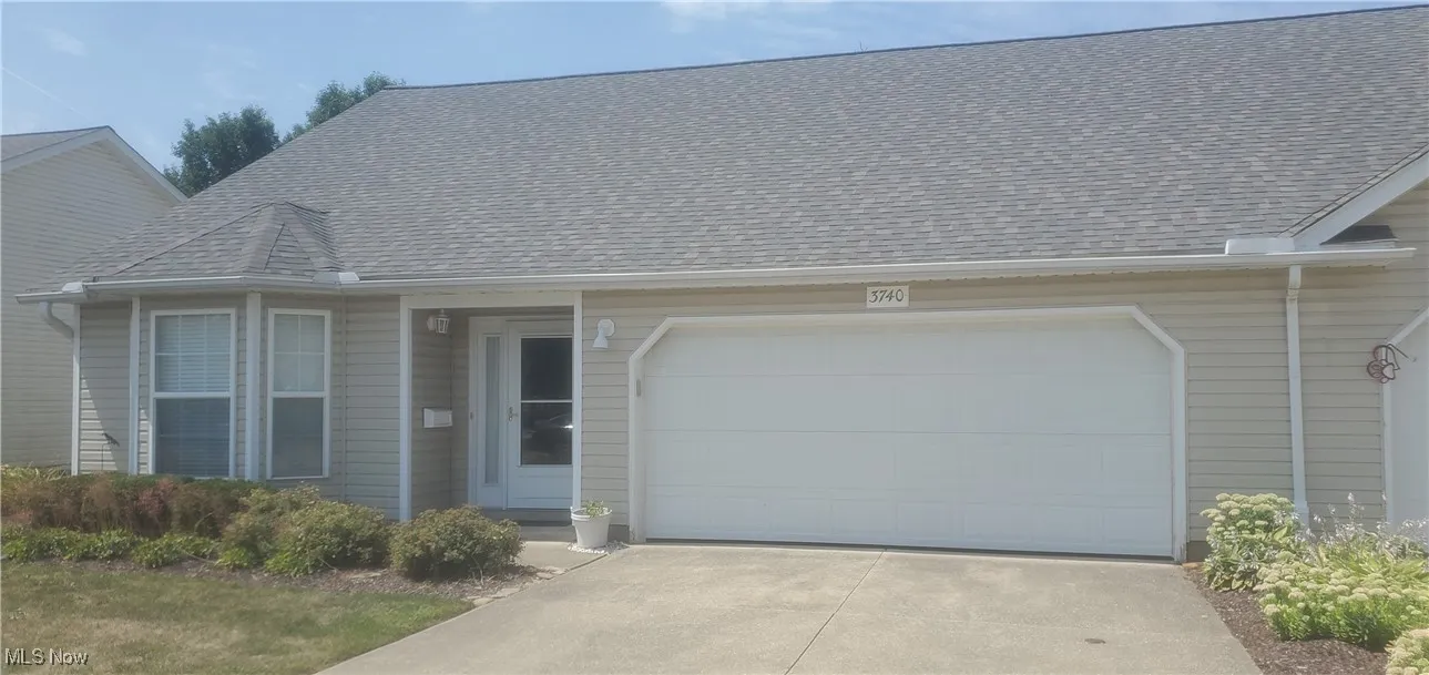 View of front of house with an attached garage, roof with shingles, and driveway