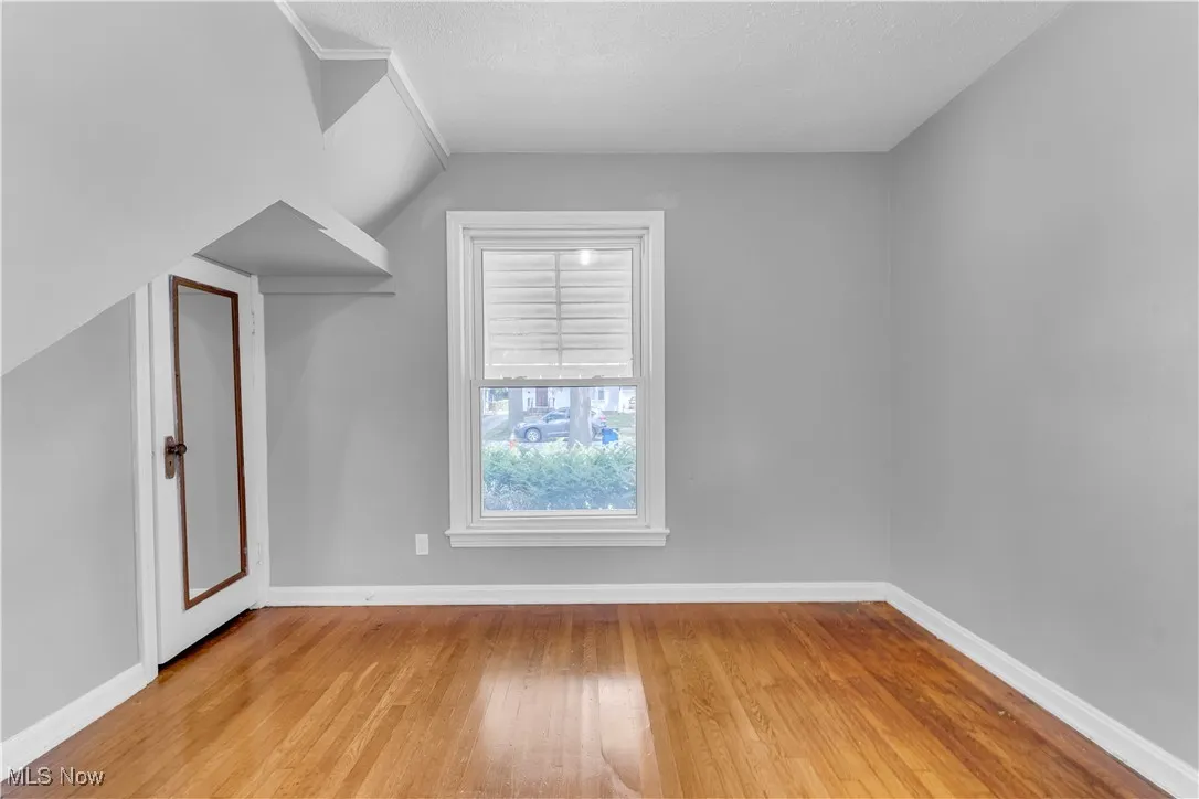 Additional living space with light wood finished floors, a textured ceiling, and lofted ceiling
