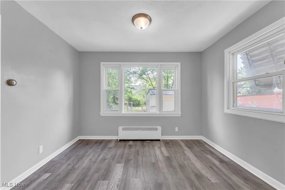 Unfurnished room featuring wood finished floors and radiator heating unit