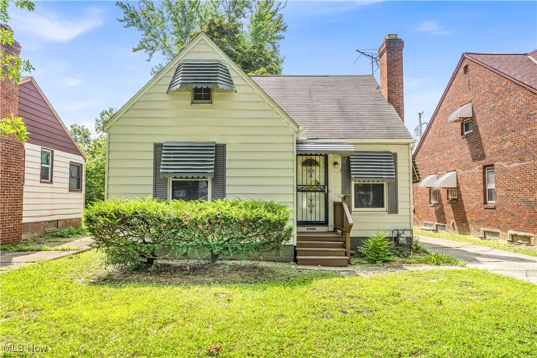 Bungalow-style house with a front yard, a shingled roof, and a chimney